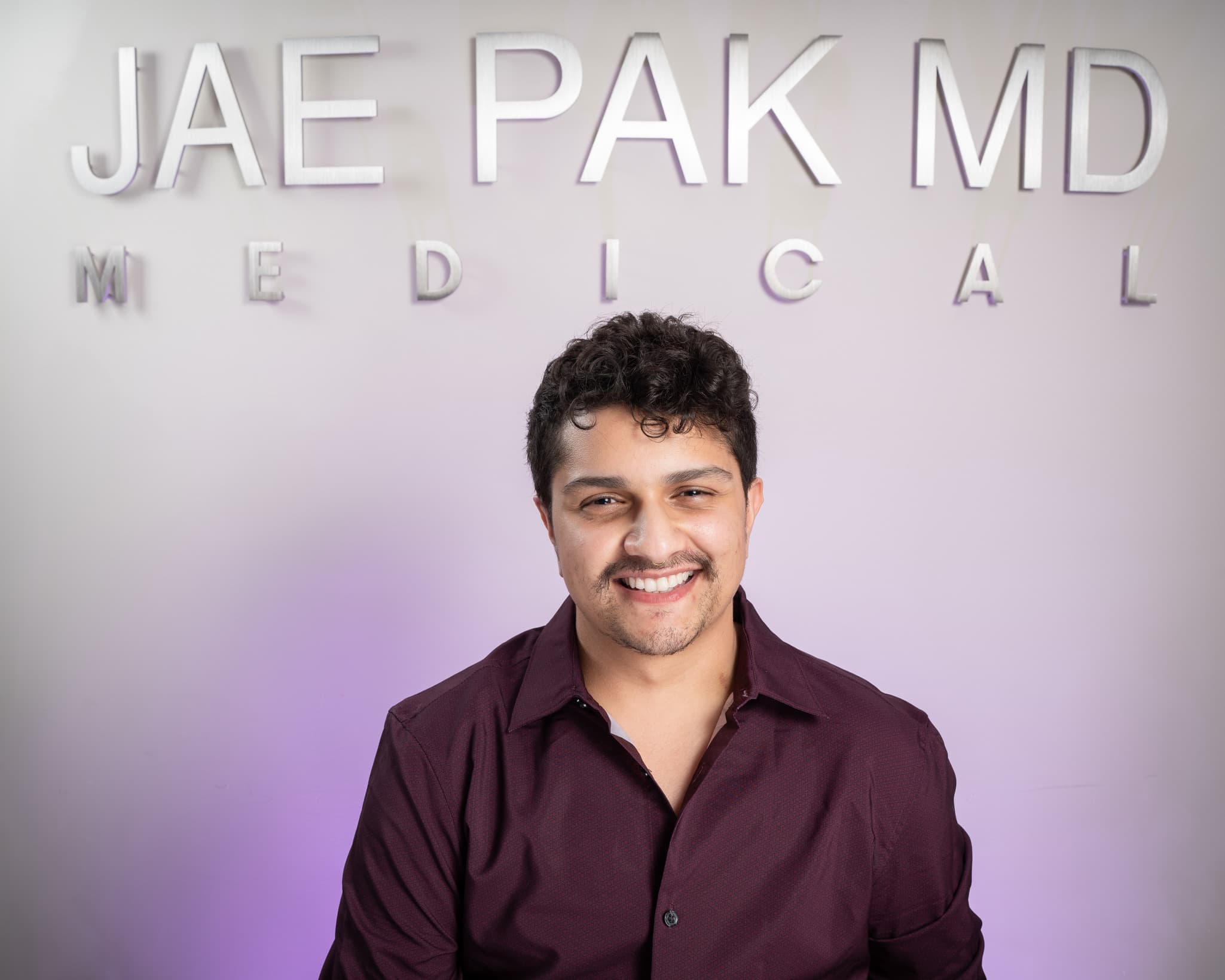 An image of a man with a big a smile had his picture taken at Dr. Jae Pak's medical clinic after his hair transplant